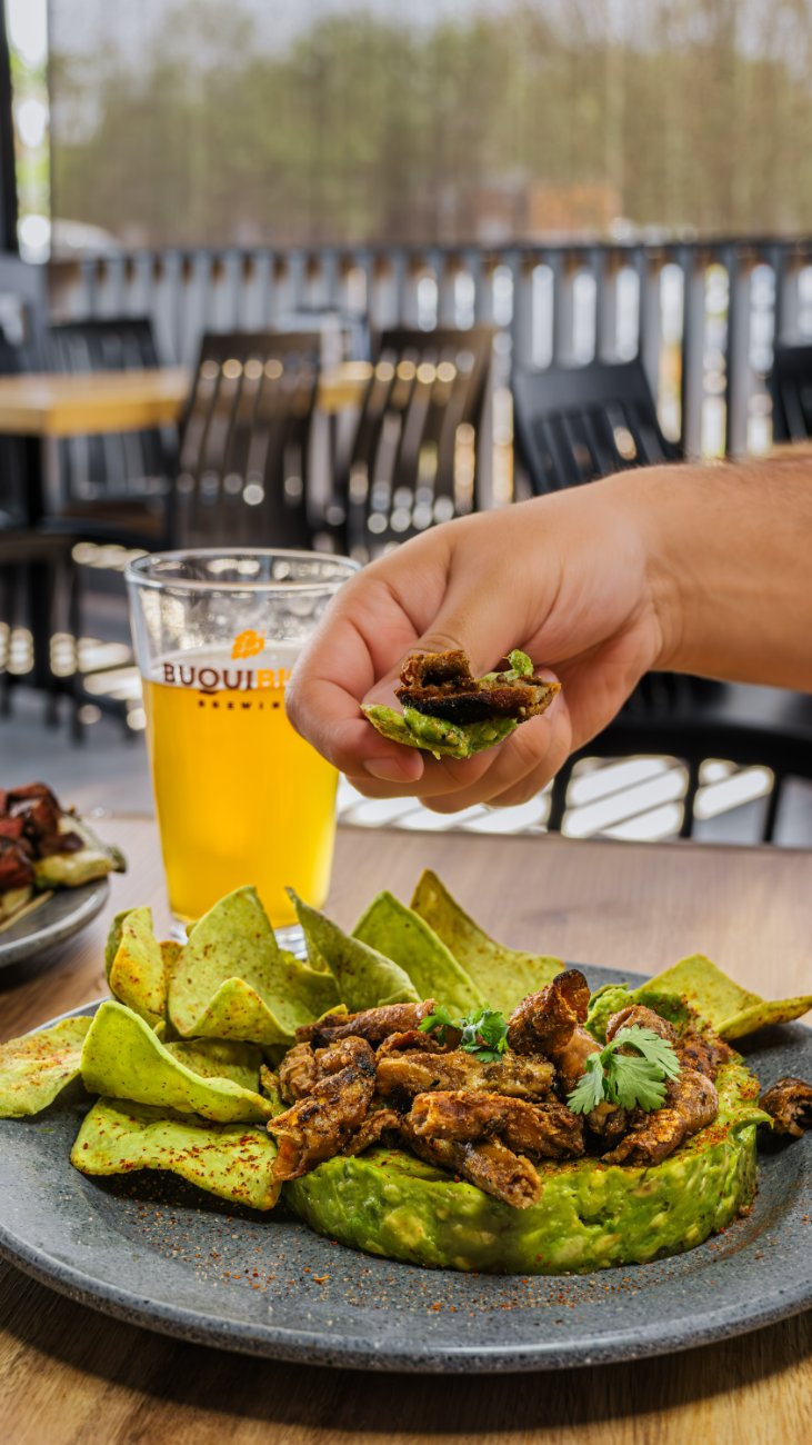 Guacamole coronado con tripa dorada, totopos verdes y cerveza artesanal