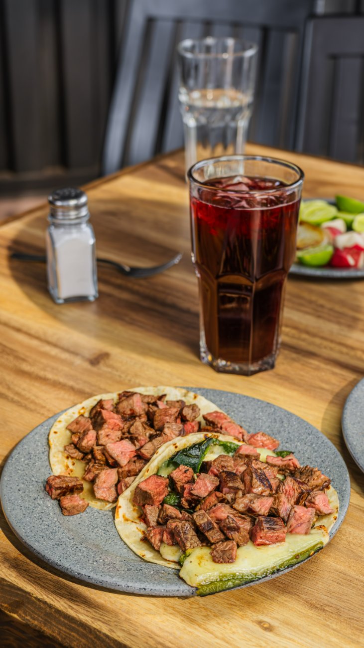 Tacos de asada acompañados de agua de jamaica
